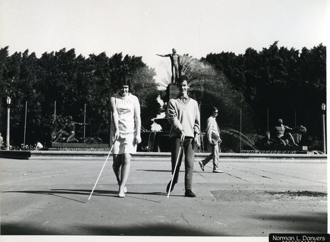 Two people using their white canes in front of Archibald Fountain in Sydney