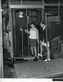 Two children use their canes to get off a bus whilst an instructor watches