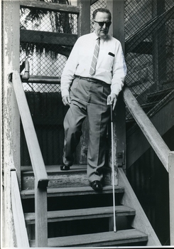 Man using a Hoover cane to descend a wooden external stairway