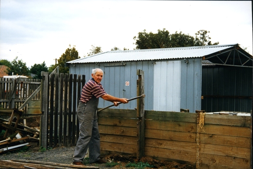 Older man in overalls removing a retaining wall