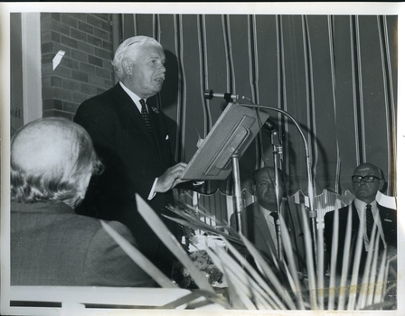 Sir Delacombe at podium giving speech