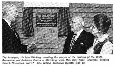 John Wicking holds cord opening curtain across plaque with Kitty Rose and John Wilson looking on
