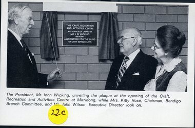 John Wicking holds cord opening curtain across plaque with Kitty Rose and John Wilson looking on