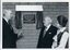 John Wicking holds cord opening curtain across plaque with Kitty Rose and John Wilson looking on