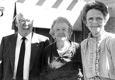 Two older women and one older man stand and smile at camera
