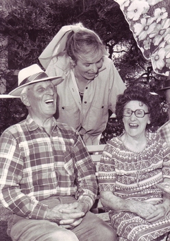 Younger woman with scarf laughs with an elderly man and woman