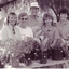 Five people stand smiling behind pots of plants