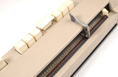 Beige rectangle box with cream buttons and braille display