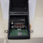 Seven silver oval keys attached to black vinyl covered device inside black box