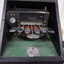 Seven silver oval keys attached to black vinyl covered device inside black box