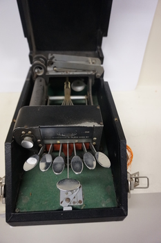 Seven silver oval keys attached to black vinyl covered device inside black box