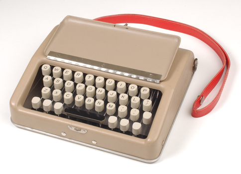 Tan case with flip top lid exposing keyboard, and red handle strap