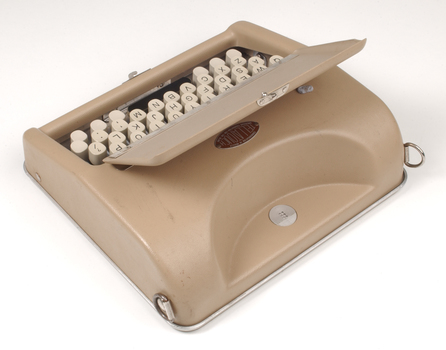 Tan case with flip top lid exposing keyboard, and red handle strap