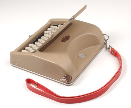 Tan case with flip top lid exposing keyboard, and red handle strap