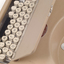 Tan case with flip top lid exposing keyboard, and red handle strap