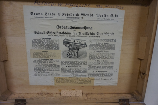 Paper attached to lid of box in German, describing use and care of typewriter
