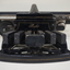 Black rectangular base with seven black keys and silver plates for producing Braille at rear