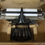Black rectangular base with seven black keys and silver plates for producing Braille at rear