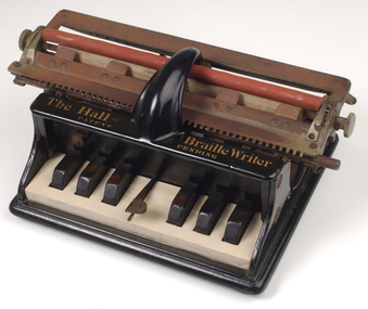 Piano like keyboard on black iron base with metal rollers