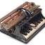 Piano like keyboard on black iron base with metal rollers