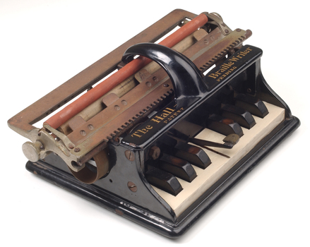 Piano like keyboard on black iron base with metal rollers