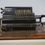 Black register shaped object on wooden board with metal levels and handles.