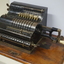 Black register shaped object on wooden board with metal levels and handles.
