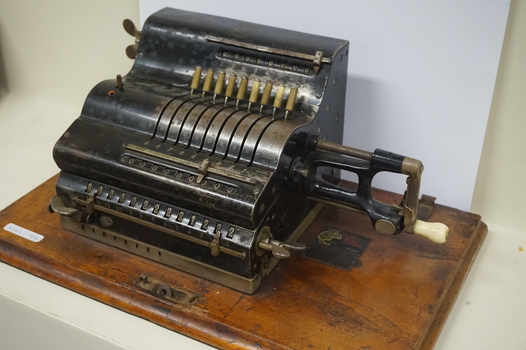 Black register shaped object on wooden board with metal levels and handles.