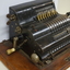 Black register shaped object on wooden board with metal levels and handles.