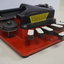 Metal braille machine with red base and 7 white wood keys