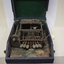 Black and silver brailler in disintegrating green felt box