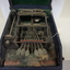 Black and silver brailler in disintegrating green felt box