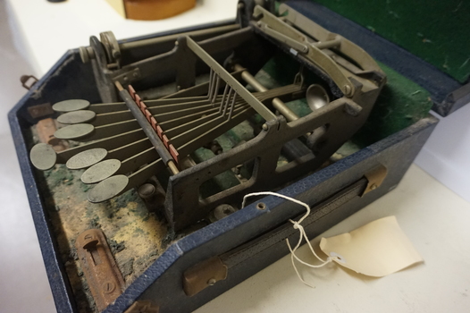 Black and silver brailler in disintegrating green felt box