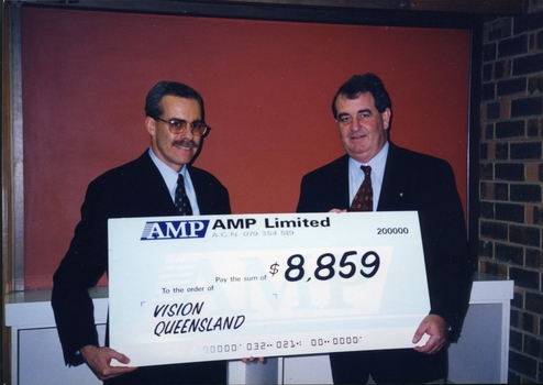 Two men hold an oversized cheque for $8859