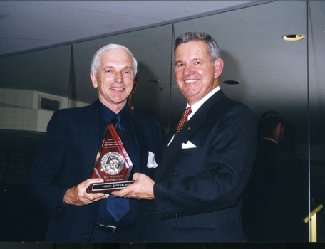 Two men in suits holding an award
