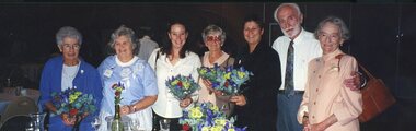 Six women and one man stand and smile for the camera at a function