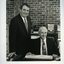 John Puttick stands beside seated Peter Lynam in an office