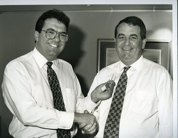 Santo Santoro shakes hands with John Puttick and holds out a silver key to him