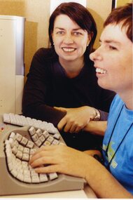 Anna Blight sits next to a person using an adaptive keyboard