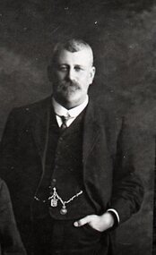 Bearded man with hand in waistcoat pocket near his fob watch