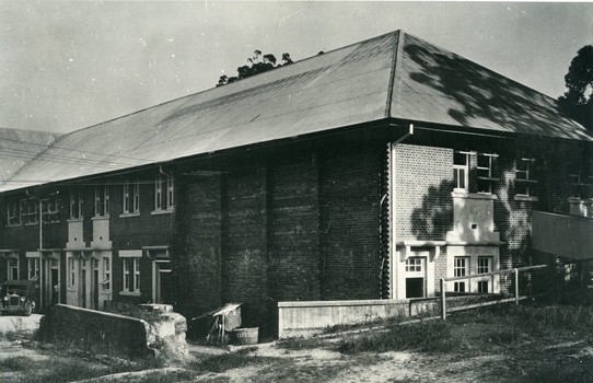 Brick two storey building with 1920's car on side