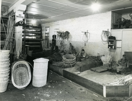 Four men making wicket baskets with some completed baskets displayed