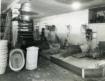 Four men making wicket baskets with some completed baskets displayed