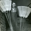 Male holds two different lengths of millet brooms in a doorway