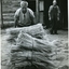 One man pushes a trolley of millet stalks whilst another watches