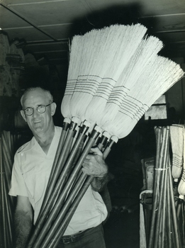 Older man lifting completed millet brooms