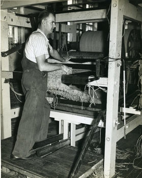 Man operating a standing loom in the workshop