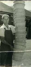 Man holds 12 cane baskets which tower above his head