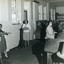 Four women standing or sitting at various workstations