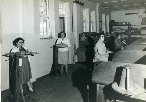 Four women standing or sitting at various workstations